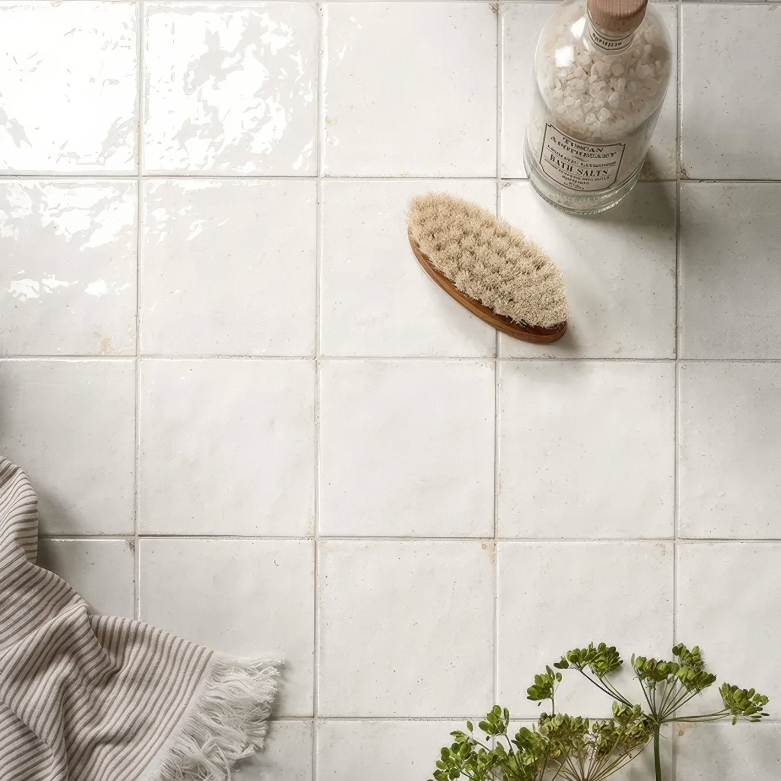 A natural-bristle bath brush with a smooth light brown wooden handle on arte italiano blanco porcelain tiles