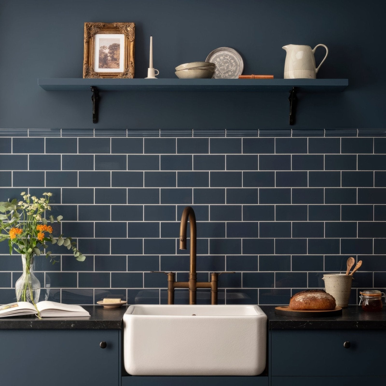 White farmhouse sink with a bronze faucet set against dark blue subway tile backsplash in ascot blue albert moulding