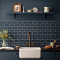 White farmhouse sink with a bronze faucet set against dark blue subway tile backsplash in ascot blue albert moulding