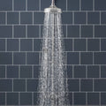 Showerhead with sleek polished chrome finish and multiple water jets dispersing wide spray for ascot blue field tile