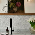 Athens Carrara Marble Mosaic white marble herringbone mosaic behind a sink with a black kitchen tap