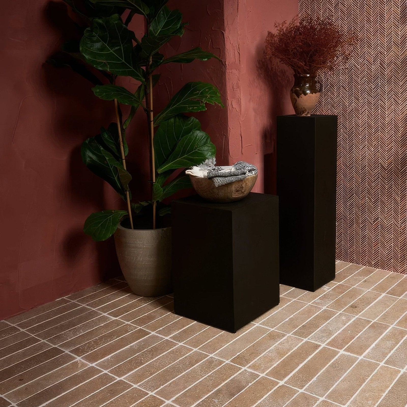 A rustic terracotta bowl with matte finish holding folded gray and white fabric in athens rosso travertine mosaic style