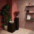Athens Rosso Travertine Mosaic reddish-brown travertine herringbone mosaic on a wall above a wooden shelf with a canvas tote bag