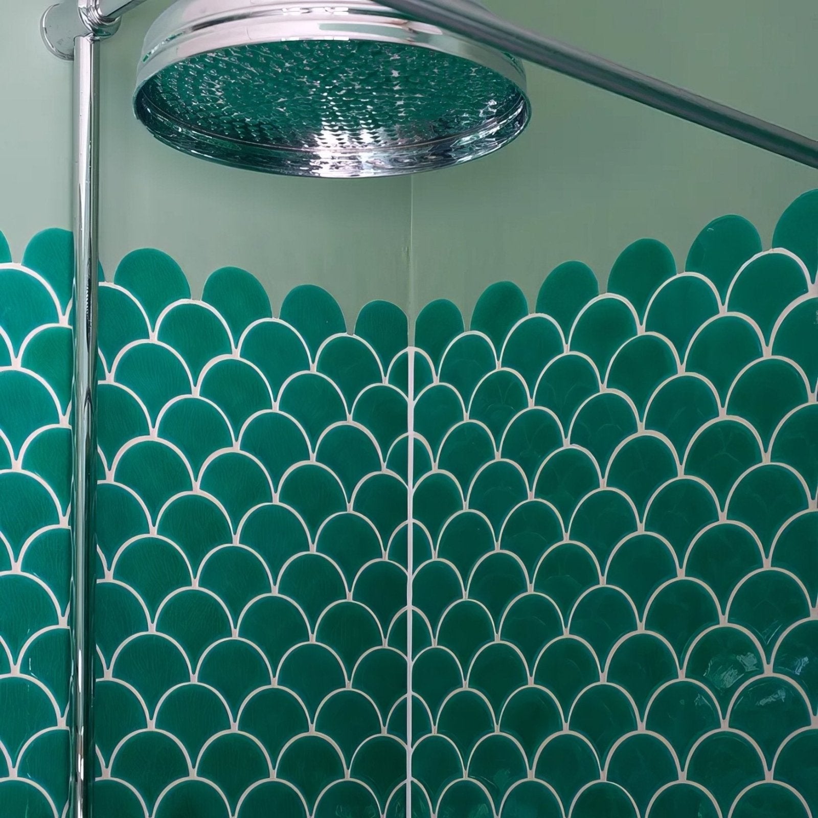 Chrome finished showerhead with hammered texture above emerald green atlantis porcelain mosaic fish scale tiles