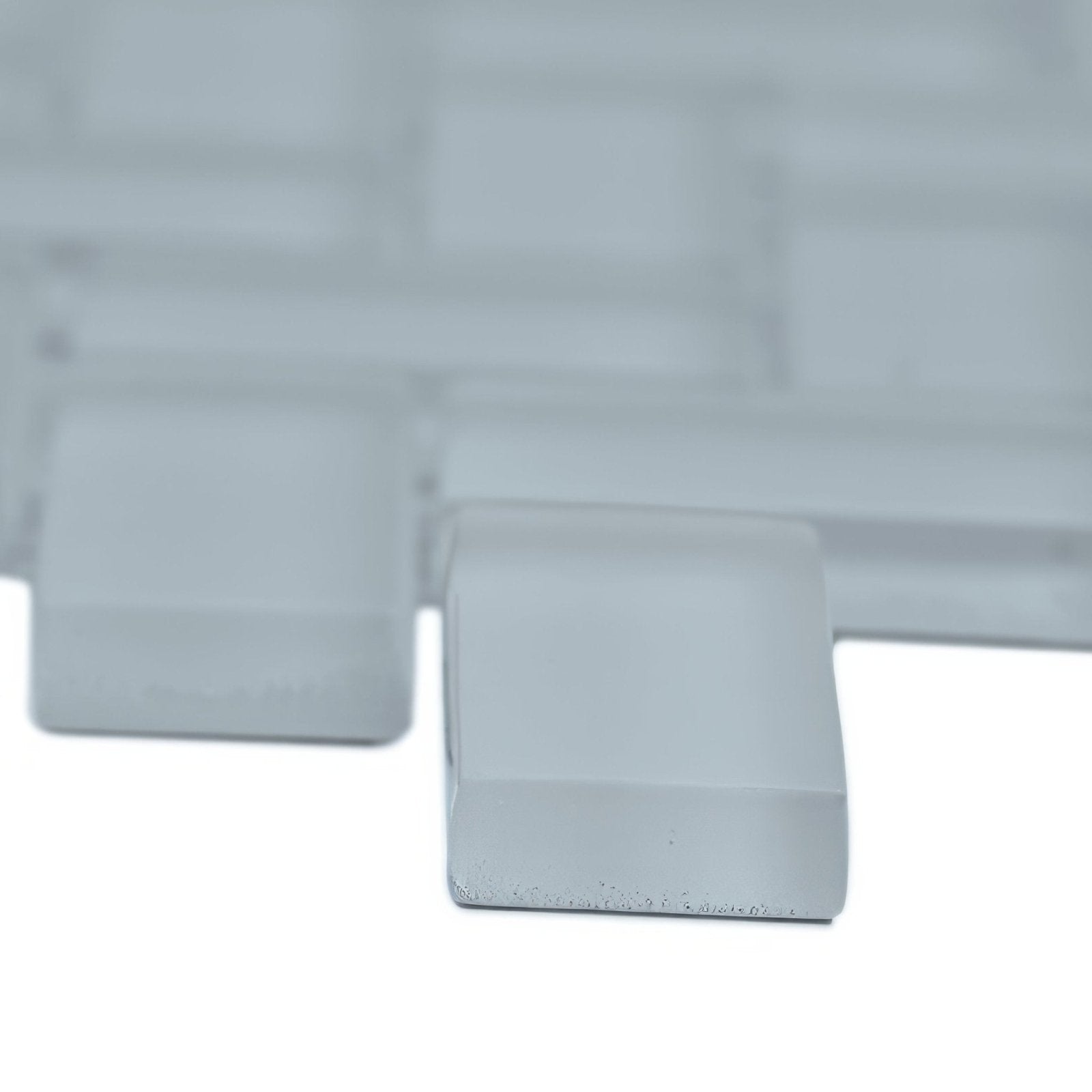 White rectangular glass mosaic tile with frosted finish and subtle reflective edges in Aurora herringbone grey mosaic design