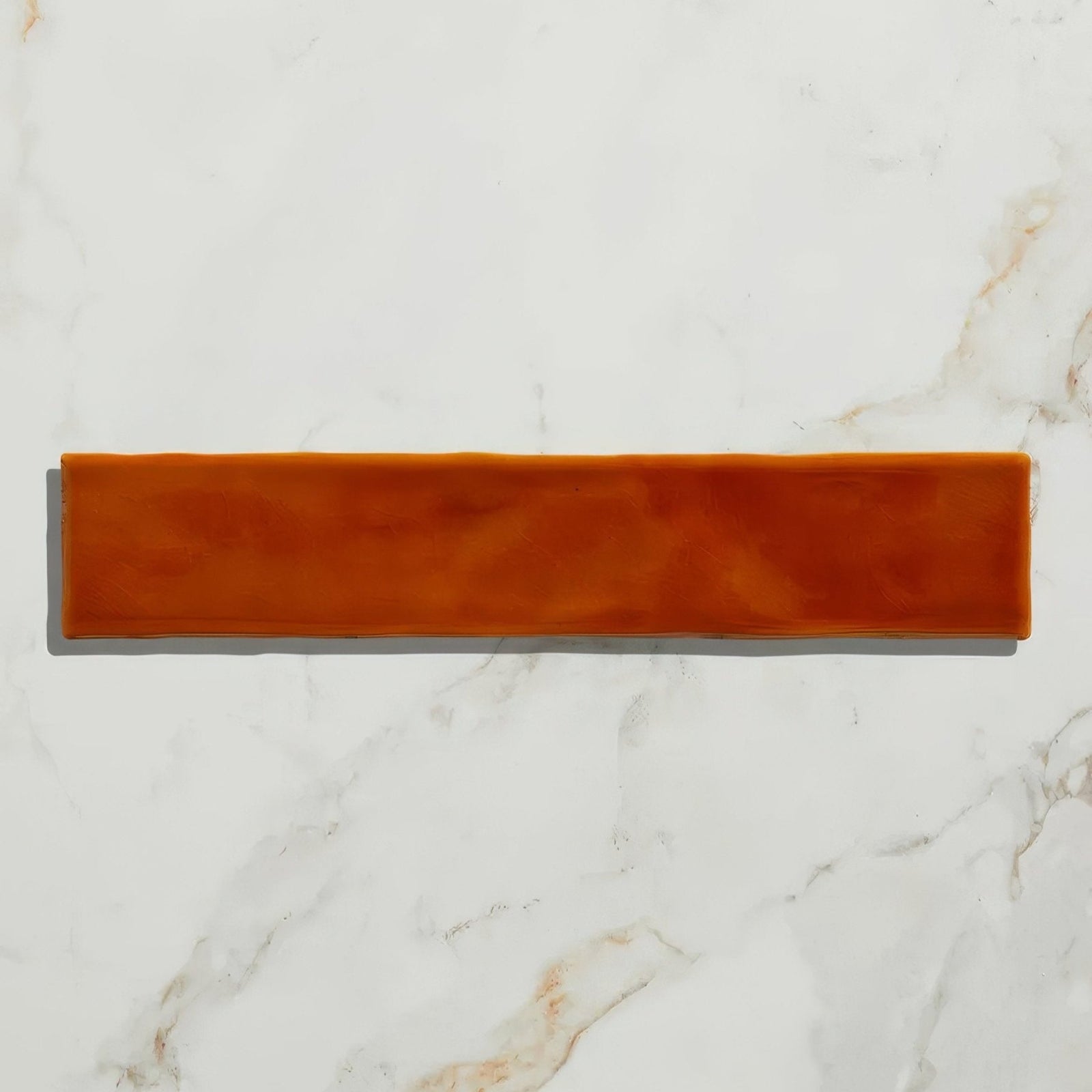 A rectangular matte orange ceramic tile with a smooth slightly textured surface from avebury ceramic burnt caramel