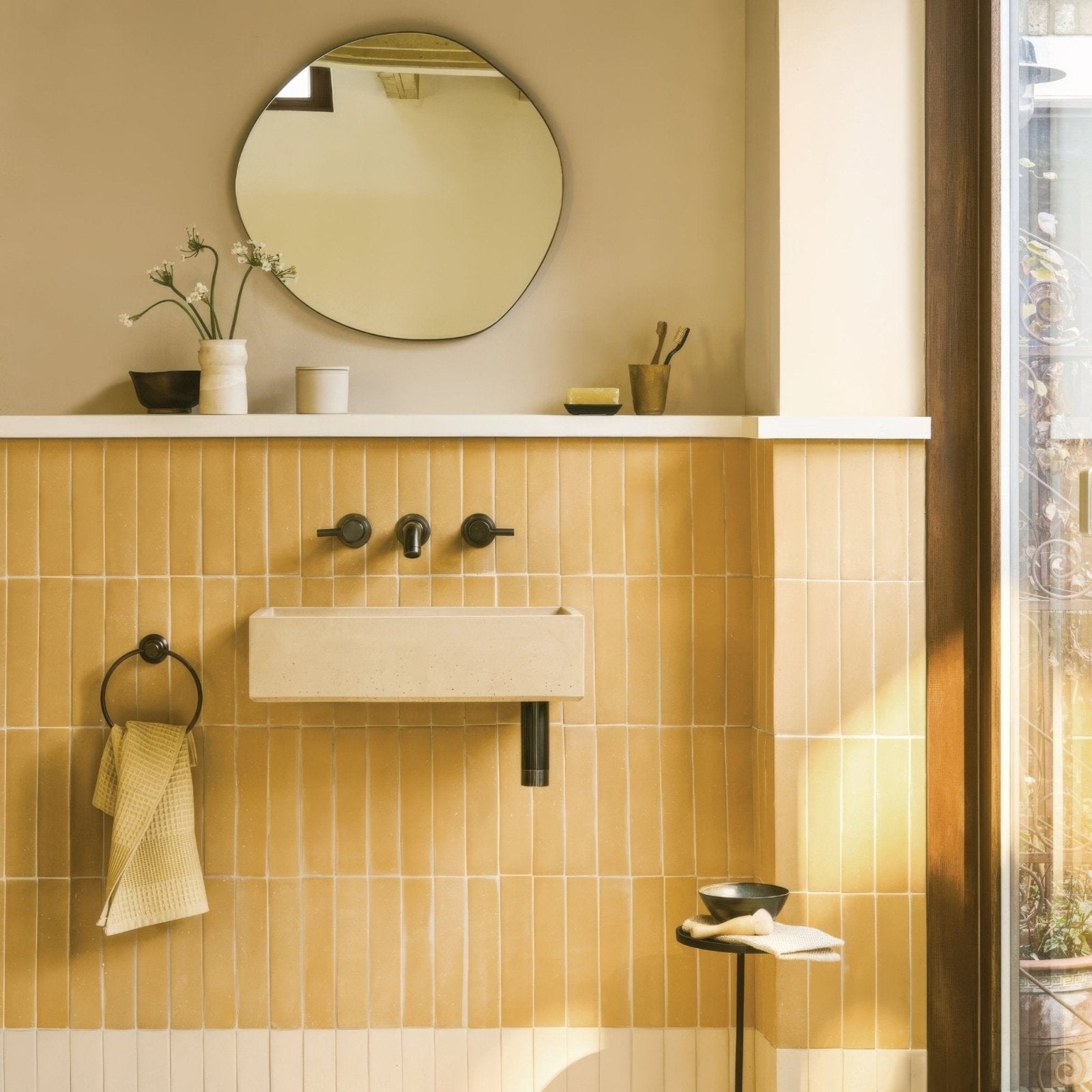 Cream-colored rectangular wall-mounted sink balance sand tile with sleek black faucet fixtures