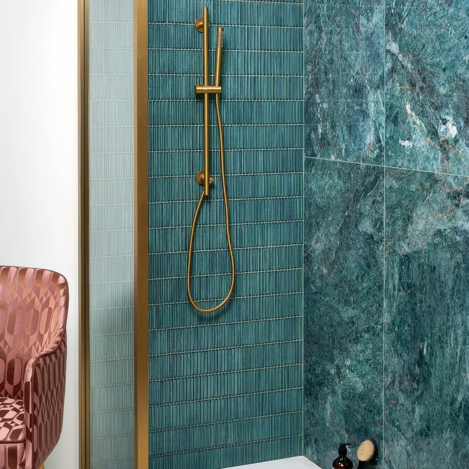 Gold-toned showerhead with sleek modern design and flexible hose mounted on bamboo porcelain mosaic verdigris fixture