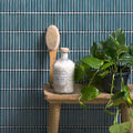 Bamboo Porcelain Mosaic Verdigris teal green ribbed porcelain mosaic styled with a glass bottle of bath salts