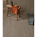 Rustic wooden stool with rough hewn legs and weathered surface topped by orange towel in Beach Hut Porcelain Caramel style