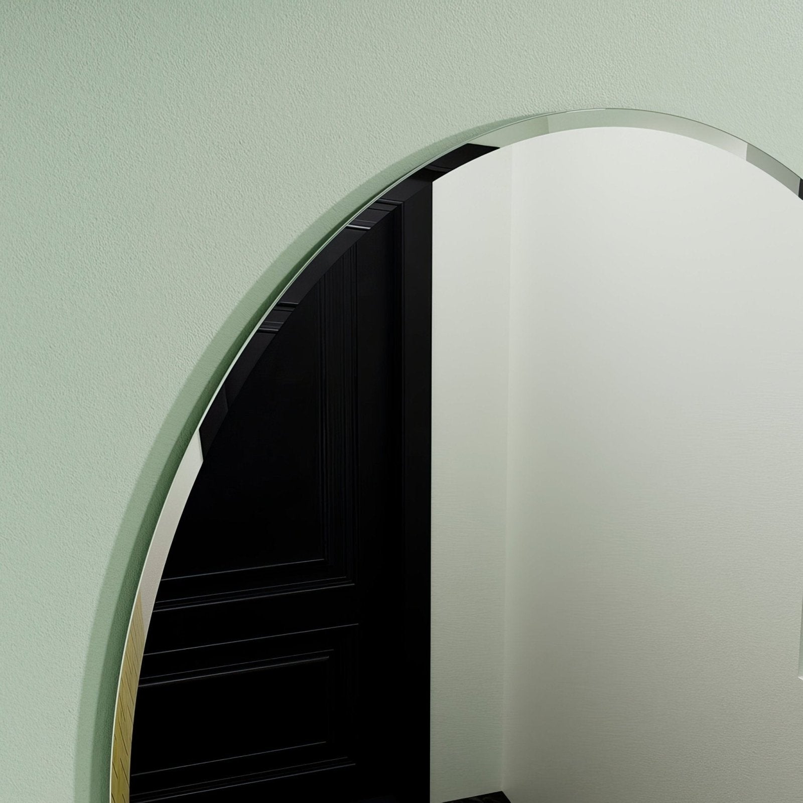 Arched belvoir oval mirror 55 with a thin metallic frame reflecting a black door and staircase