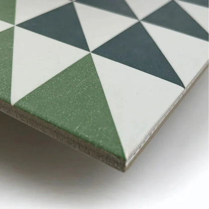 Square ceramic tile featuring a geometric pattern of green white and dark gray triangles from bert and may green majadas porcelain