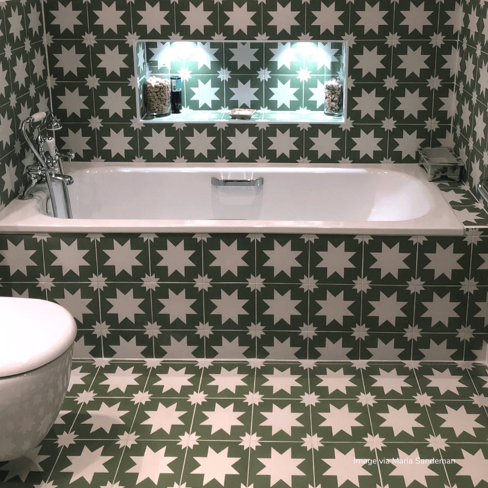White porcelain bathtub with chrome fixtures against green and white star-patterned bert & may pradena tiles