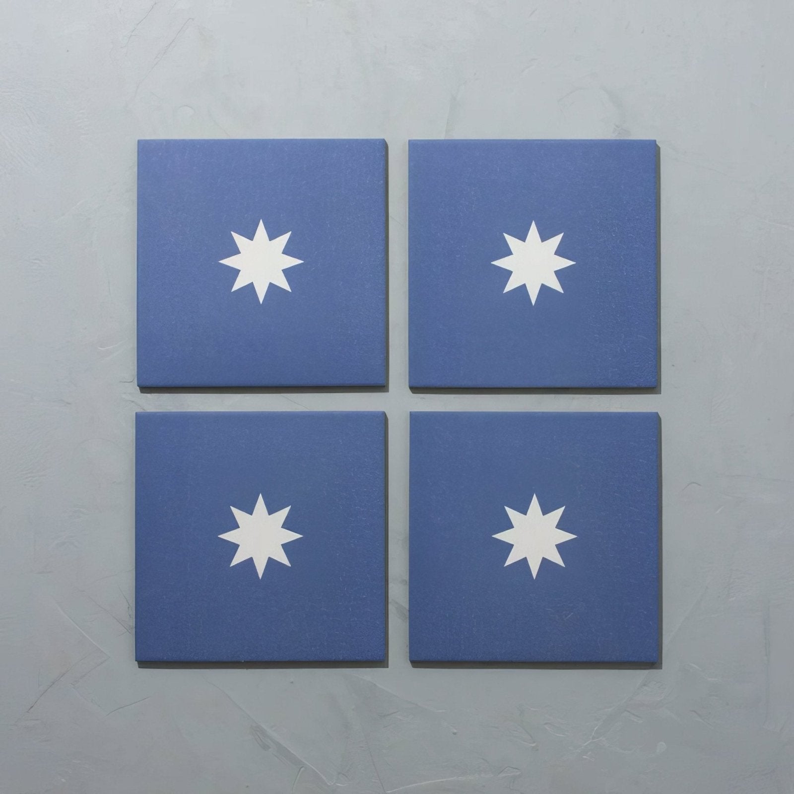 Set of four bert and may navy luna porcelain tiles in blue with white starburst design for wall or floor use