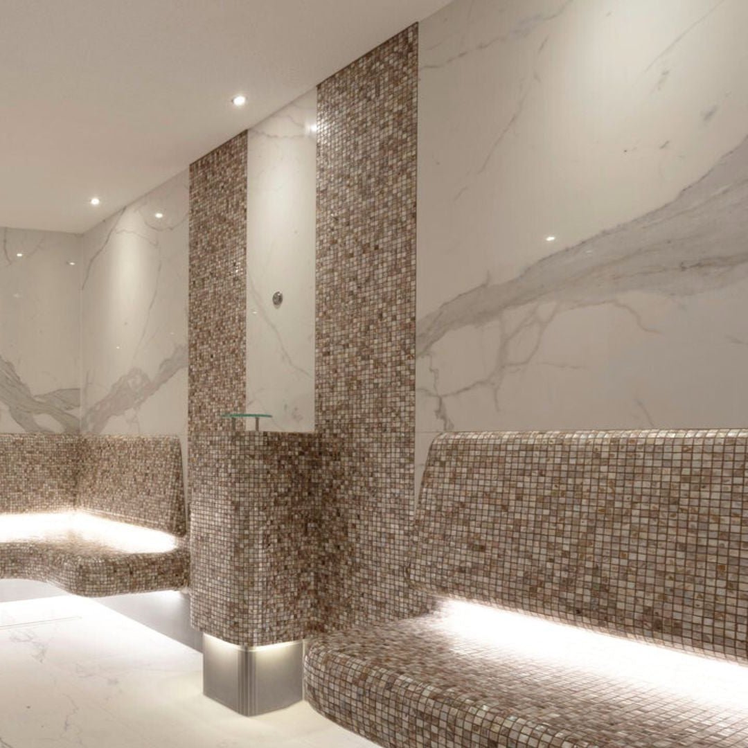 Luxurious beige and brown mosaic tiled sauna with biscotti 25mm square built-in benches and columns