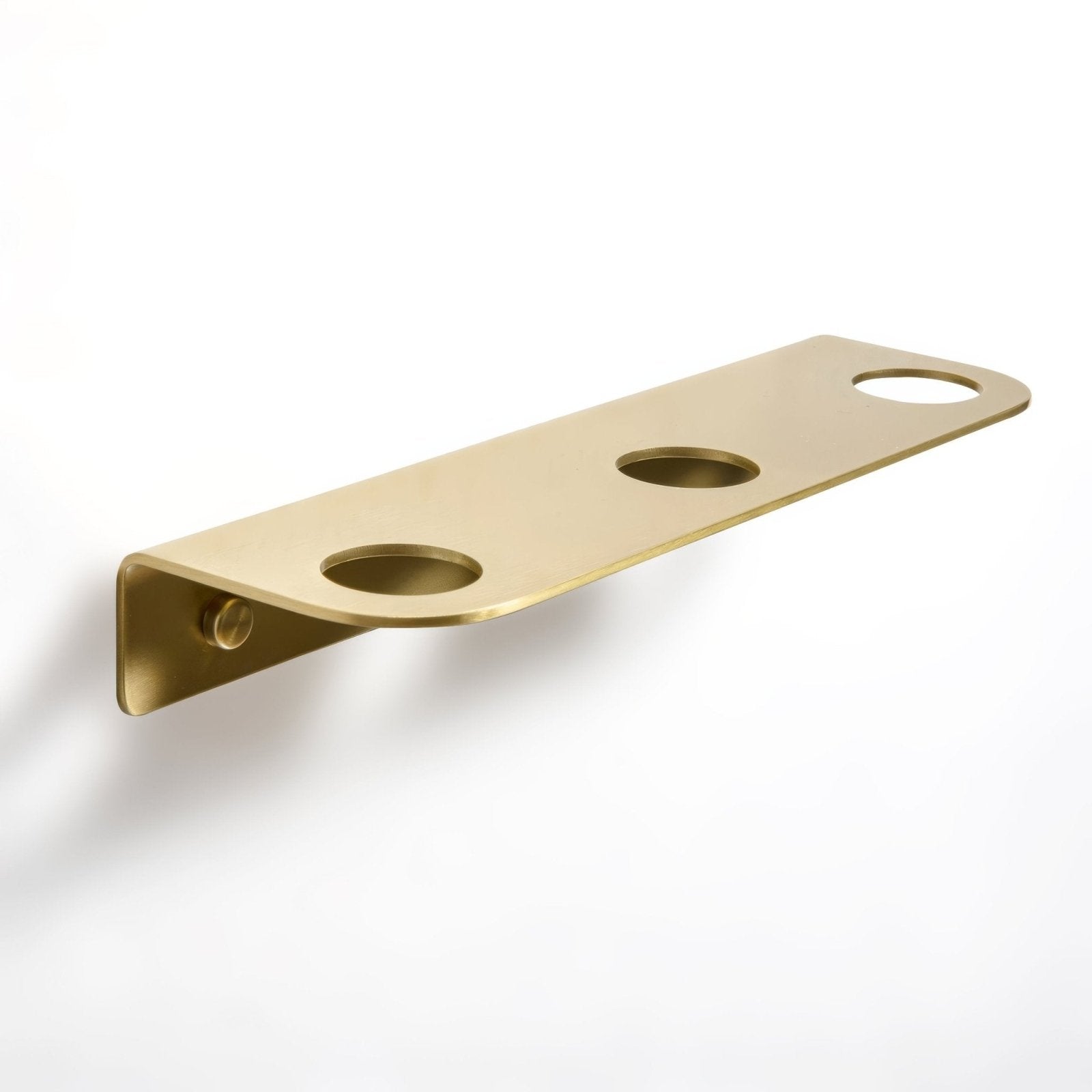 Gold-colored brass wall-mounted bottle holder with three circular cutouts for glasses or bottles in brushed brass finish