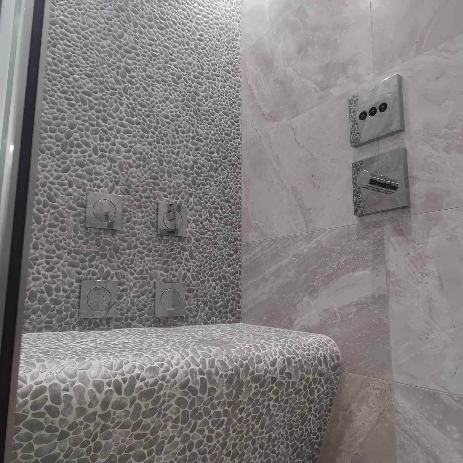 Boulder Grey Mosaic grey pebble mosaic on a shower bench with matching wall tiles