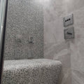 Boulder Grey Mosaic grey pebble mosaic on a shower bench with matching wall tiles