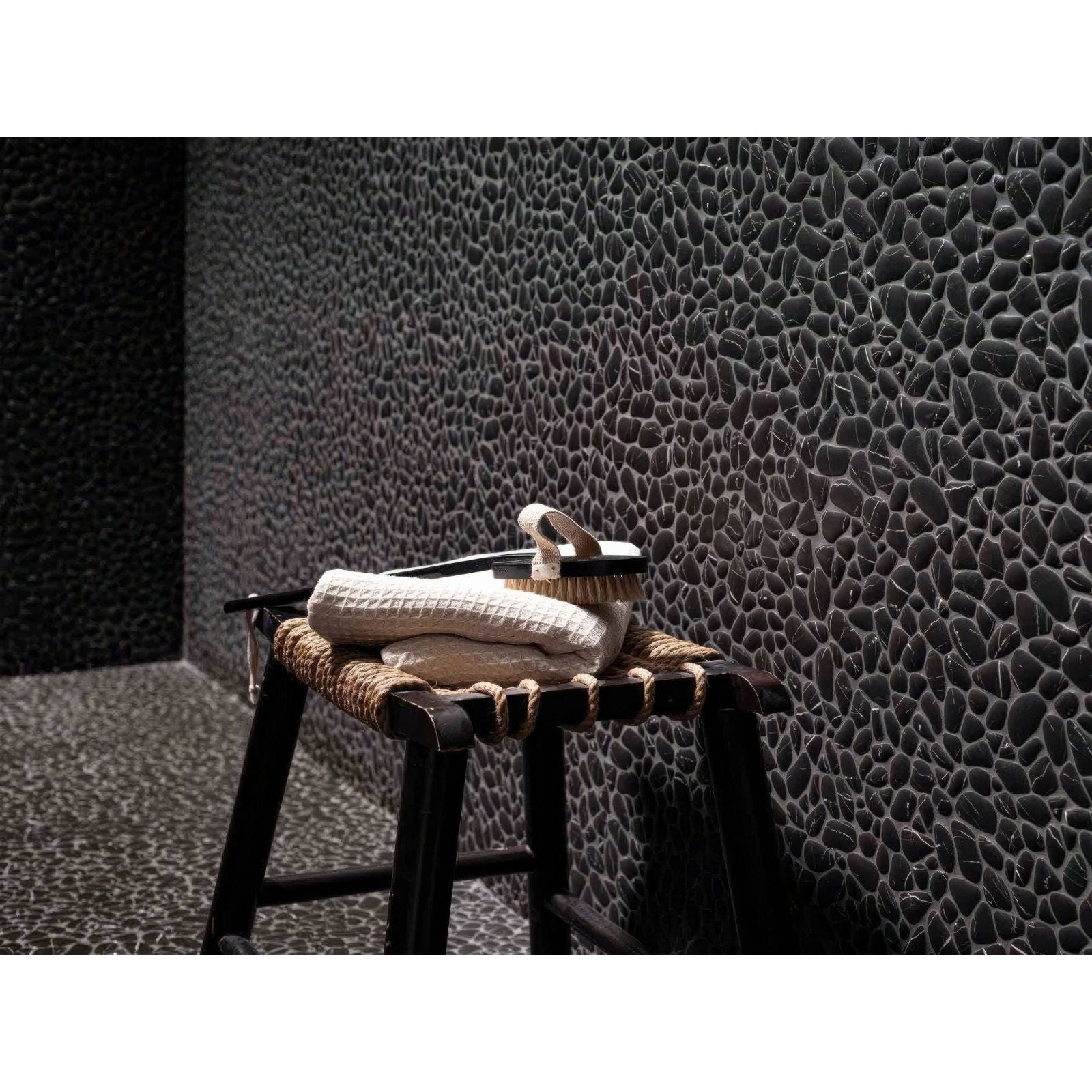 Boulder Negro Marquina Mosaic black marble pebble mosaic styled with a towel, brush and woven stool