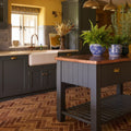 Dark gray wooden kitchen island with copper countertop and blue and white ceramic planters brewhouse porcelain parquet