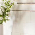 A sleek white ceramic vase with fresh white bellflowers displayed on brilliant white field tile