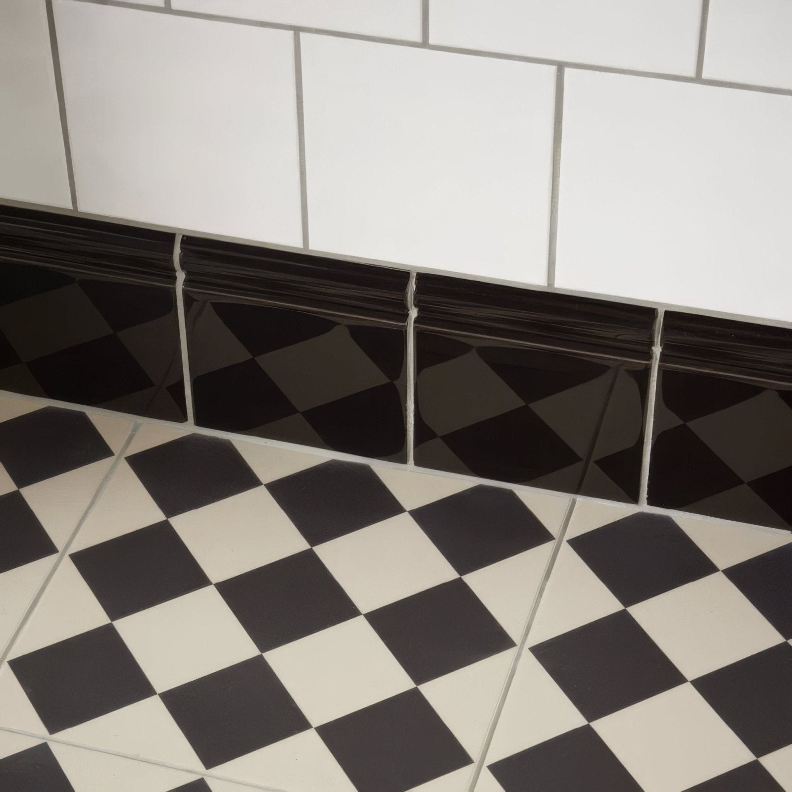 Black glossy diamond patterned tile trim installed along a white brilliant white field tile wall