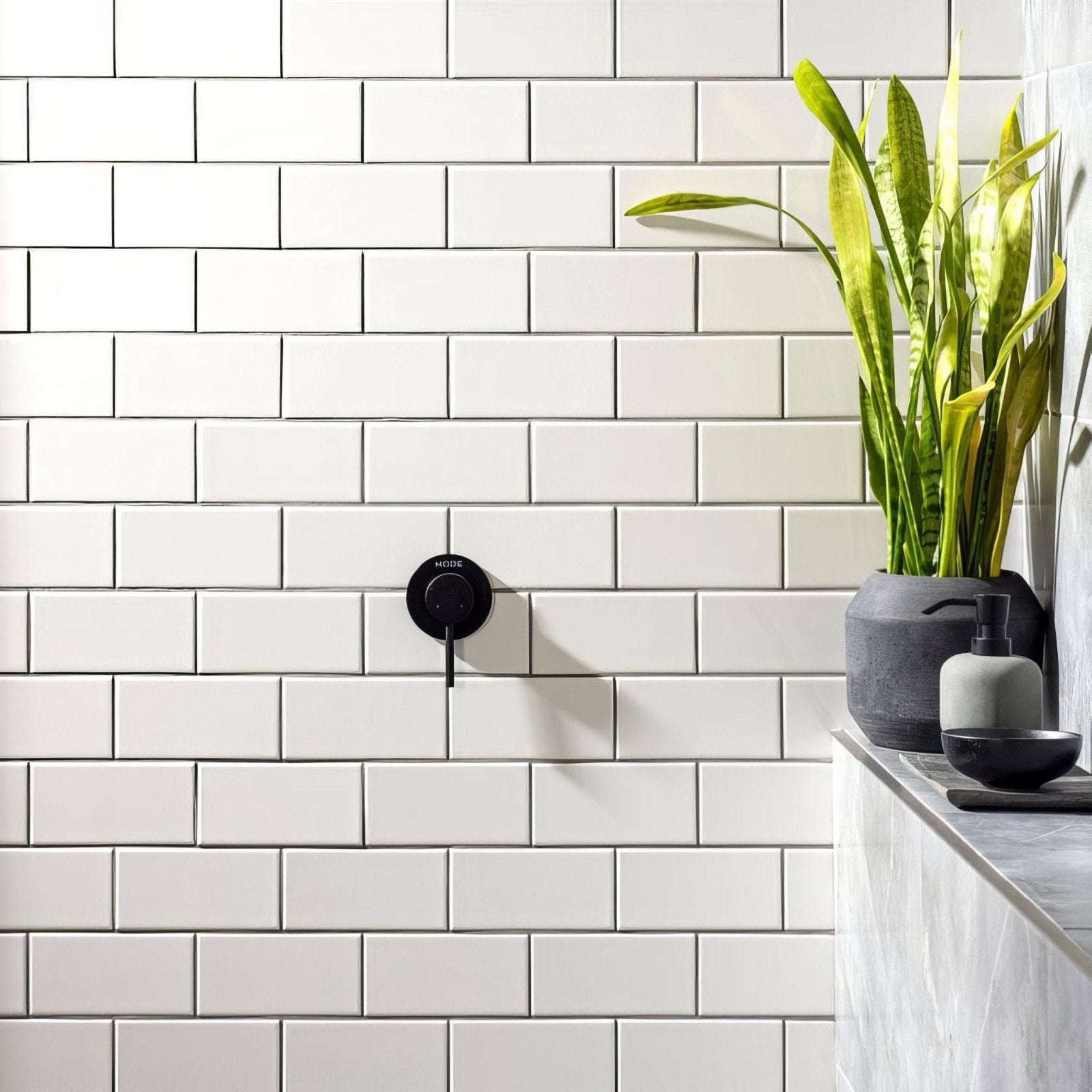 Black matte-finish wall-mounted faucet with sleek circular design and morse branding on brilliant white half tile background