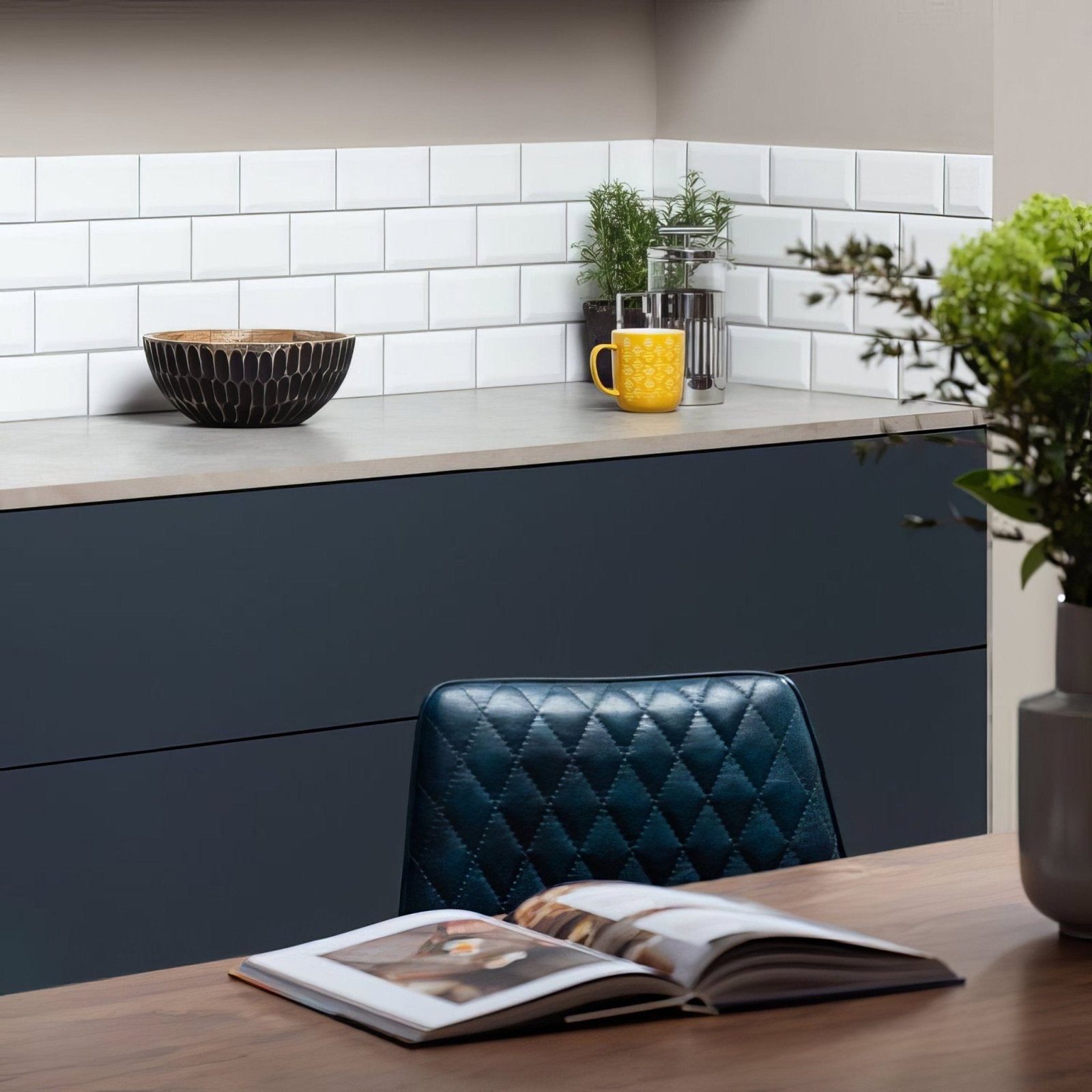 A dark teal quilted leather chair with diamond-stitched pattern next to brilliant white metro bevelled tile wall