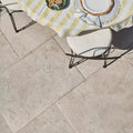 A white cushioned chair with black metal legs on a light beige brit stone burford porcelain paving patio