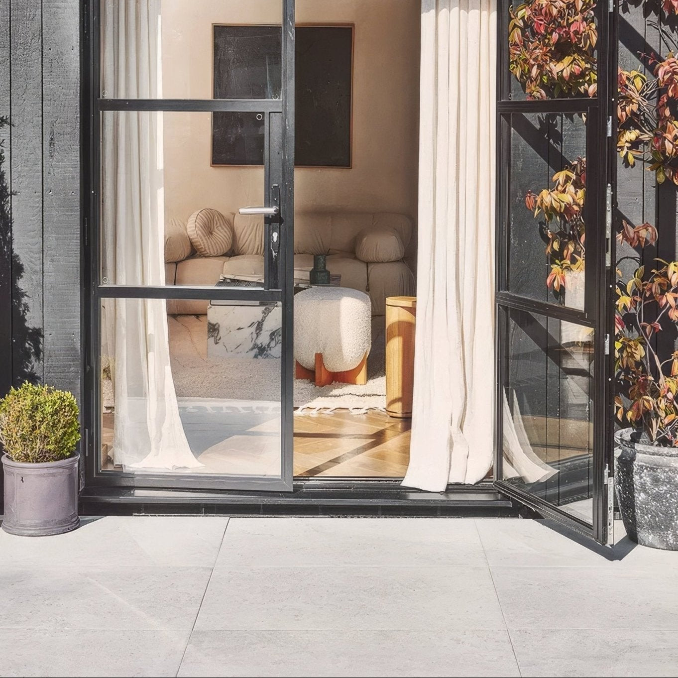 Black-framed glass sliding door with sheer white curtains and brit stone minster porcelain paving in modern interior