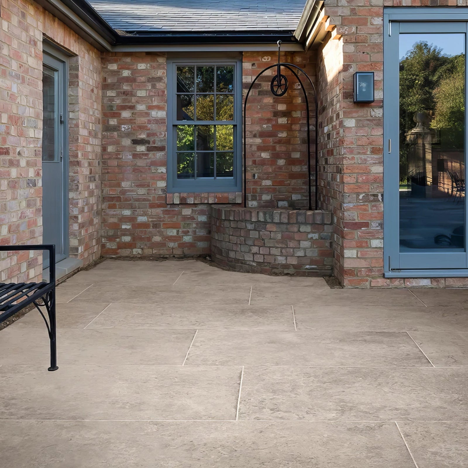 Beige stone patio tiles with subtle texture and light grout lines in brit stone pennant porcelain paving