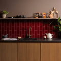 A glossy red burgundy large brick subway tile backsplash with white grout lines for kitchen walls