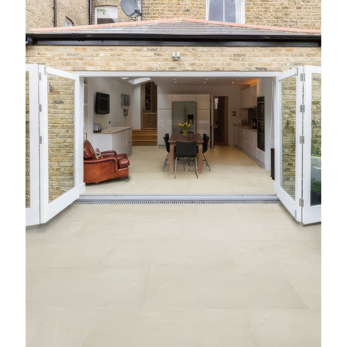 White bi-fold patio doors with sleek modern design and glass panels paired with Buscot limestone paving etched finish