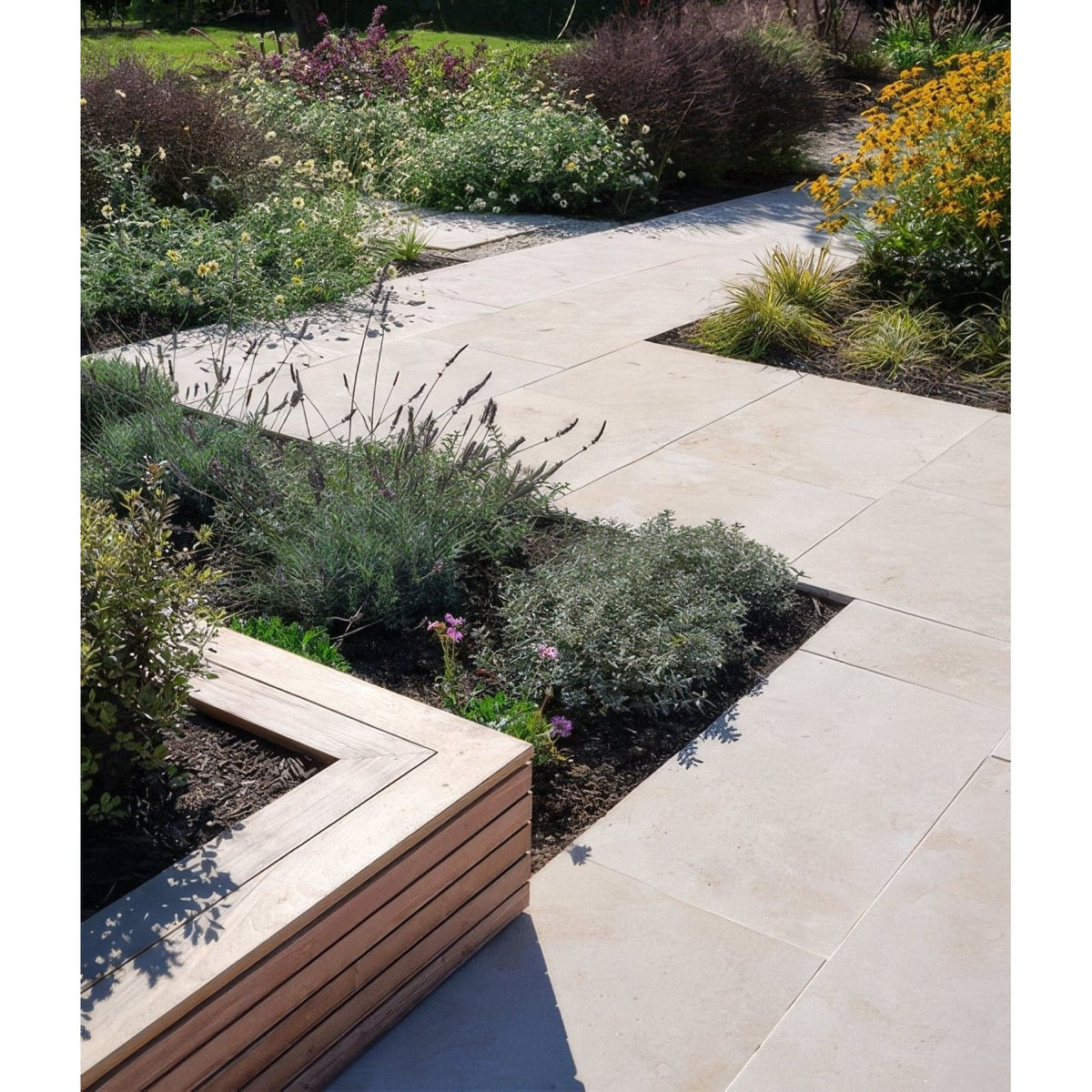 Beige buscot limestone paving with etched finish used as a stone pathway alongside a wooden planter box