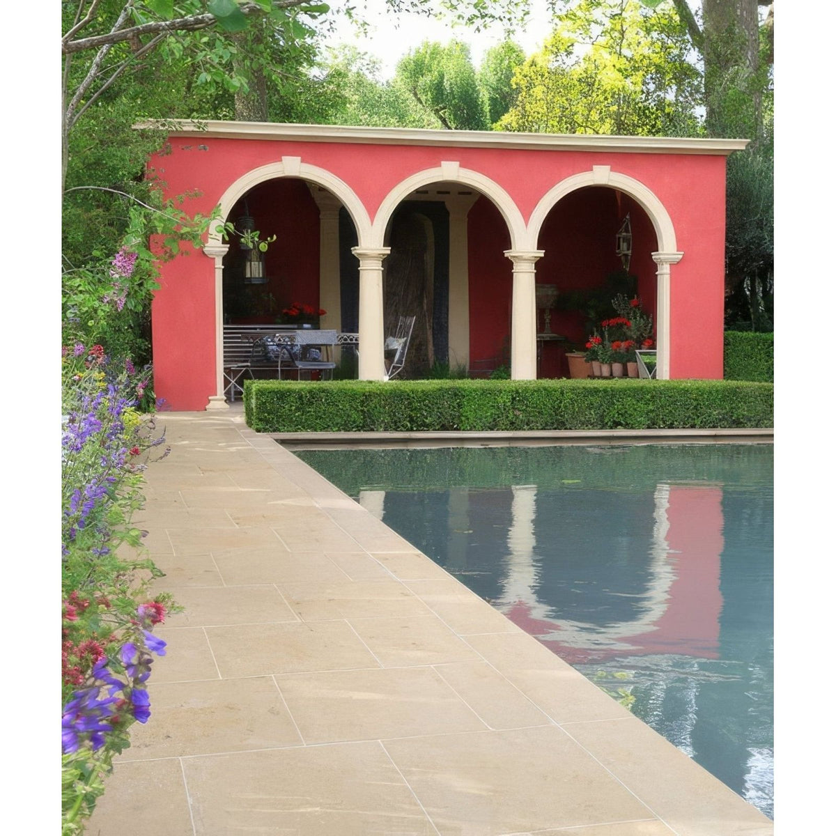 A vibrant red arched pavilion with cream limestone columns reflected in a serene pool showcases buscot limestone paving tumbled and etched finish