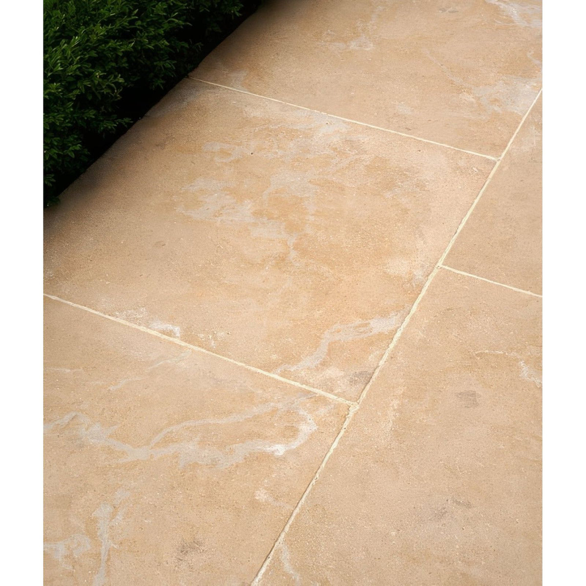 Beige buscot limestone paving tiles with natural veining and light grout lines in tumbled and etched finish