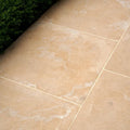 Beige buscot limestone tiles with tumbled and etched finish featuring natural veining and light grout lines
