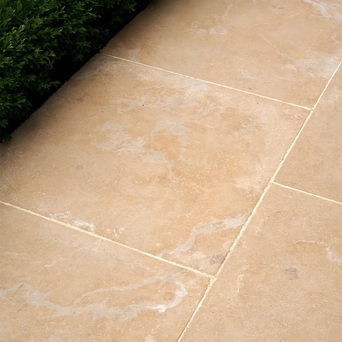 Beige buscot limestone tiles with tumbled and etched finish featuring natural veining and light grout lines