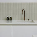 Candy Cane Porcelain Mosaic Vanilla off-white ribbed porcelain mosaic behind a bronze kitchen tap