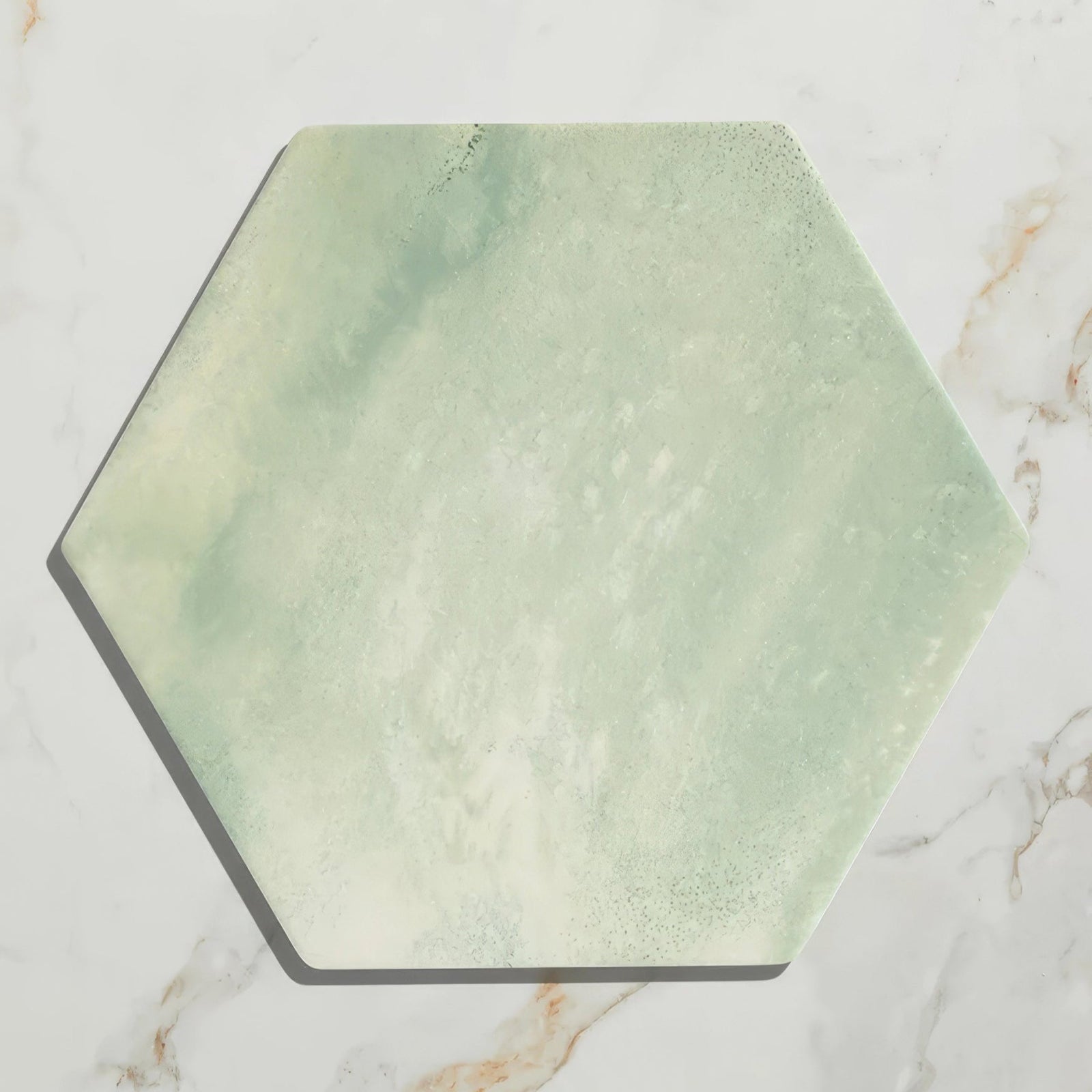 A hexagonal capri porcelain tile with a soft mottled green and white marble-like finish