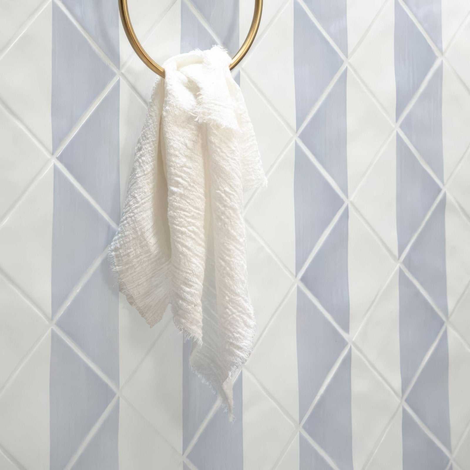 Capri Sea Mist Hand Painted Tile grey and white hand-painted tiles with a fringed towel on a gold hook