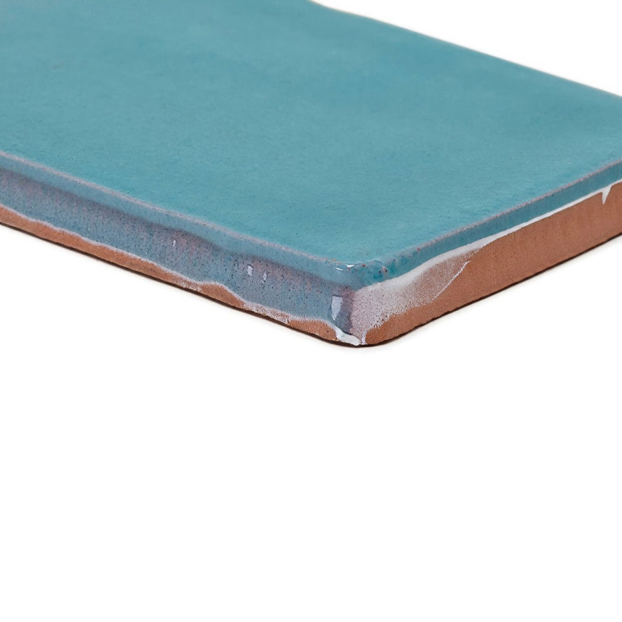 A rectangular ceramic Carnival Laredo blue glazed tile with smooth glossy teal glaze and exposed terracotta edges
