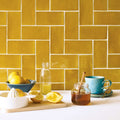 Yellow glazed ceramic tiles with white grout arranged in a herringbone pattern carnival oro yellow tile