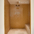 Brass showerhead with circular textured surface and polished finish in carnival oro yellow glazed tile design