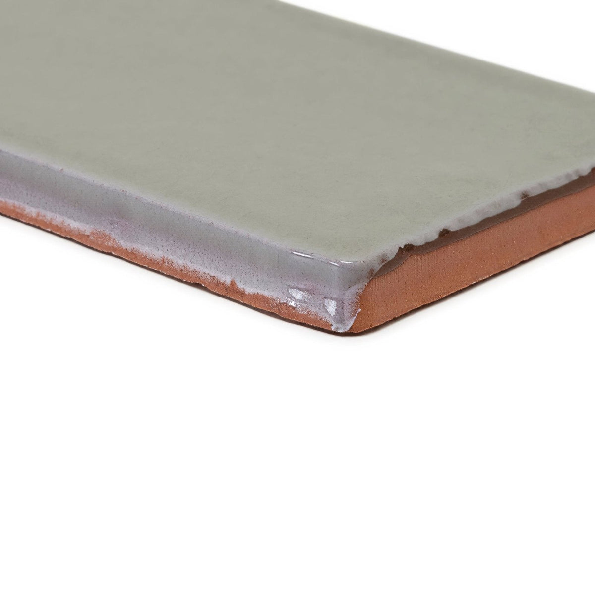 A rectangular carnival sella grey glazed tile with matte sage green glaze and exposed terracotta clay edges