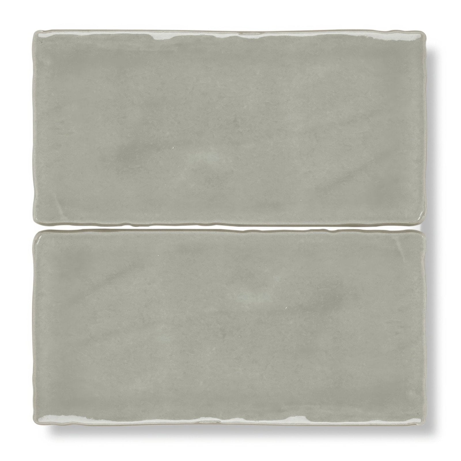 Two matte-finished gray ceramic carnival sella grey glazed rectangular tiles with slightly uneven edges