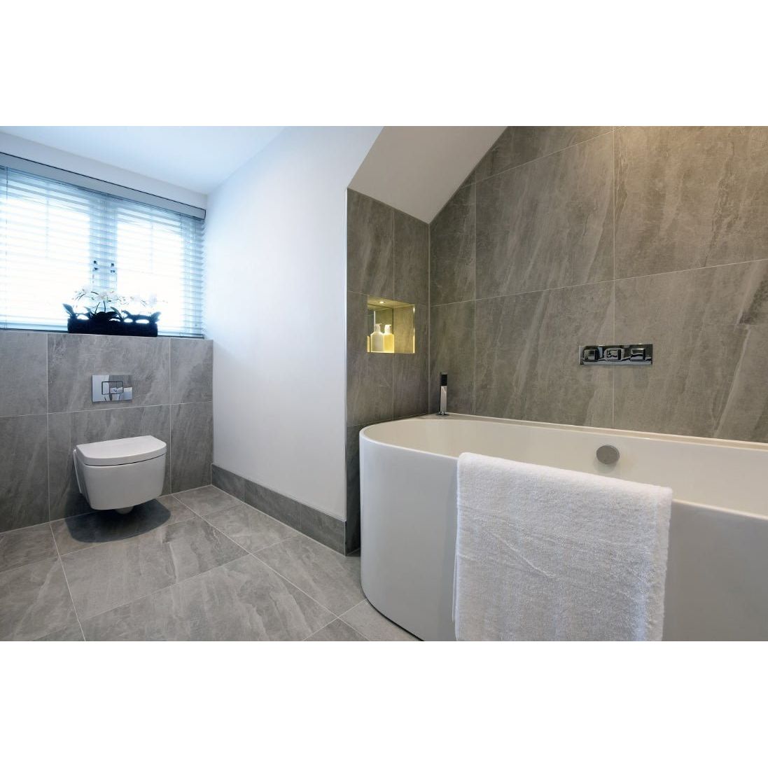 Cashmire Oyster 60 x 60cm stone-effect tiles with a towel draped over a freestanding bathtub