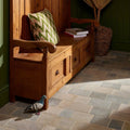 A rustic wooden bench with a green and white zigzag pillow complements castilan limestone cobbles tumbled flooring