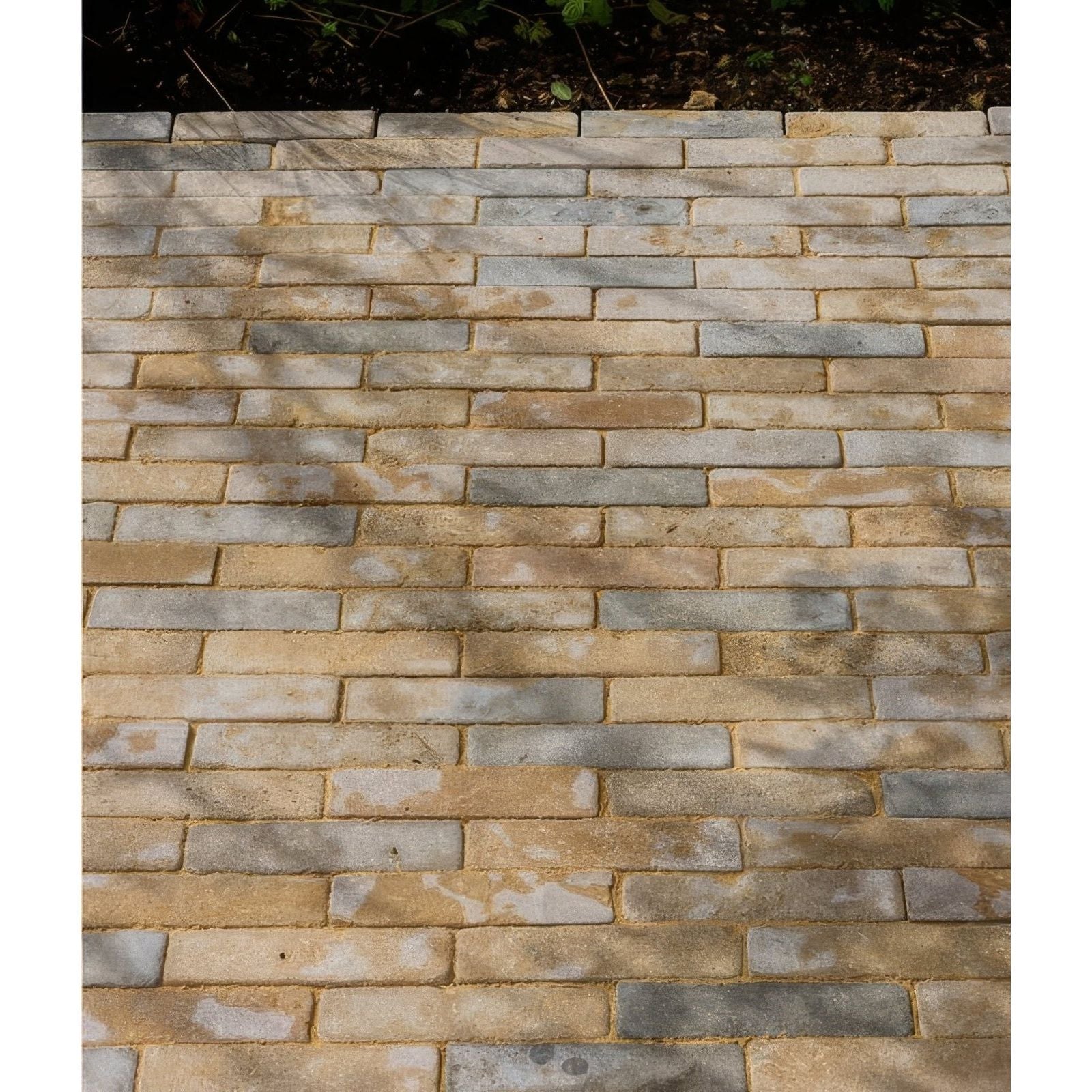 A paved walkway of castilan limestone tumbled klinkers with interlocking beige tan and gray rectangular pavers