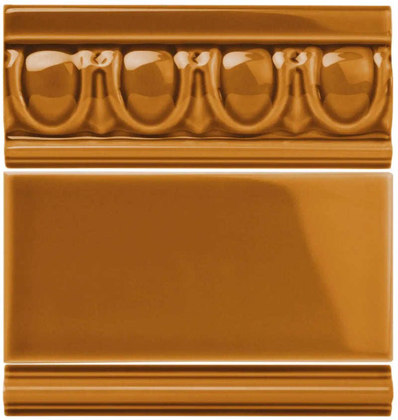 Ceramic tile with a glossy caramel finish, featuring an ornate molded border design above and below its smooth rectangular surface.
